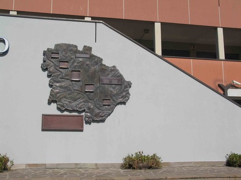 Monumento ai partigiani caduti di Pianoro, situato su una parete esterna con un design in rilievo.
