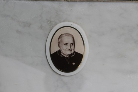 Ritratto in bianco e nero di una donna anziana con espressione serena, incorniciato su una superficie di marmo.