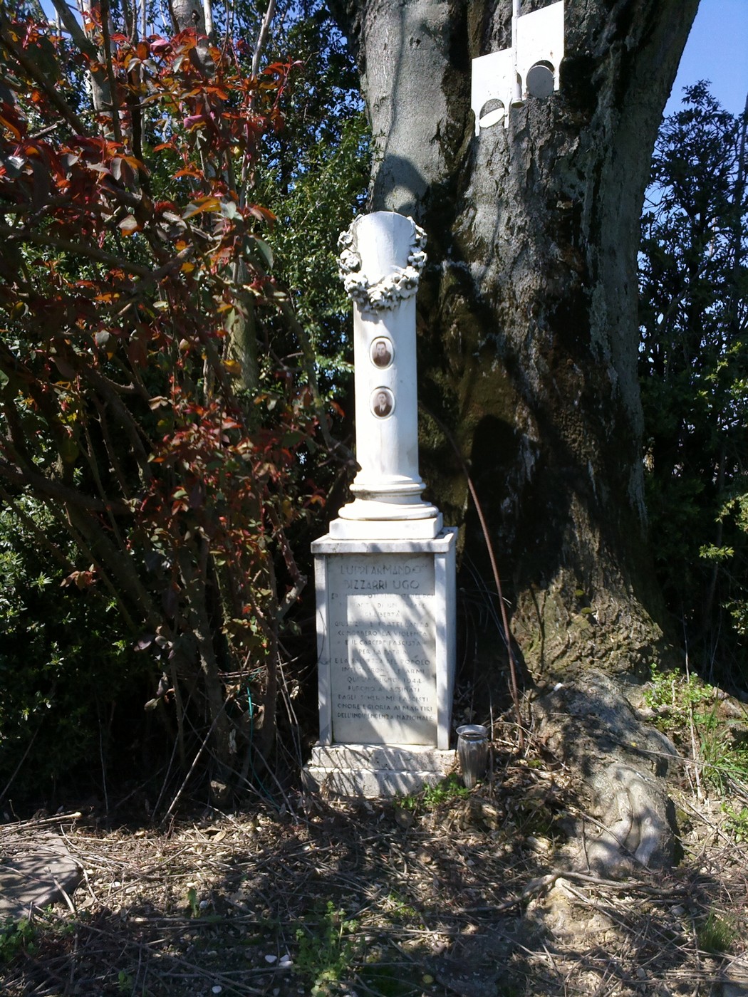 Cippo commemorativo a Luppi e Bizzarri, circondato da vegetazione, in un contesto di pace e natura.