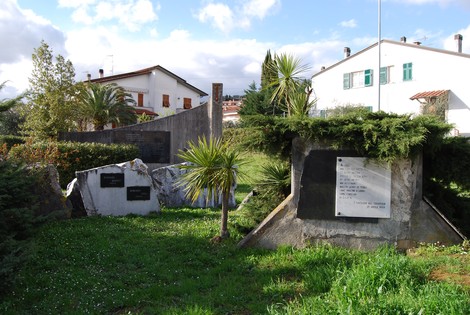 Monumento nel Parco della Resistenza di Caniparola, circondato da verde e edifici, dedicato alla memoria storica.