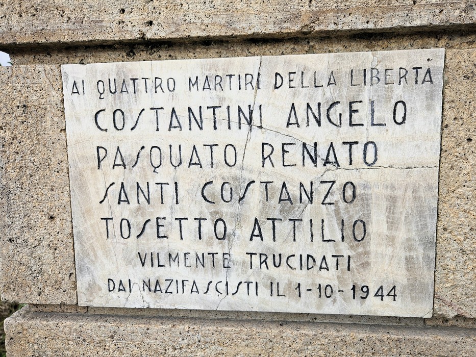 Targa in marmo con iscrizione, fissata su una parete in pietra.
