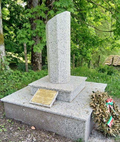 Monumento a Pasqui e Zenzocchi, con base in granito e decorazioni floreali, immerso nella natura.