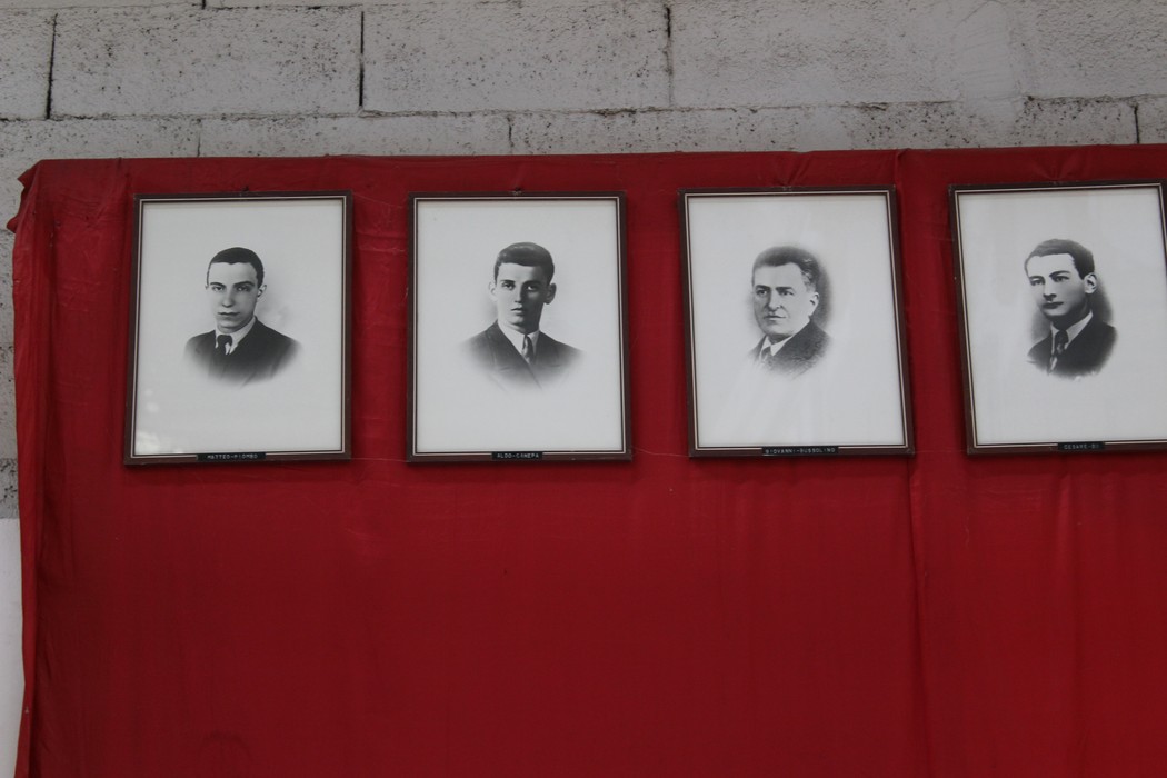 Quattro ritratti in bianco e nero appesi su uno sfondo rosso, commemorano i caduti dell'Ansaldo Elettrotecnico.