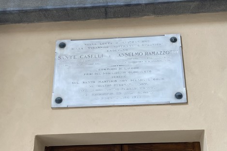 Lapide commemorativa dedicata a Sante Caselli e Anselmo Ramazzotti, situata su una muratura.