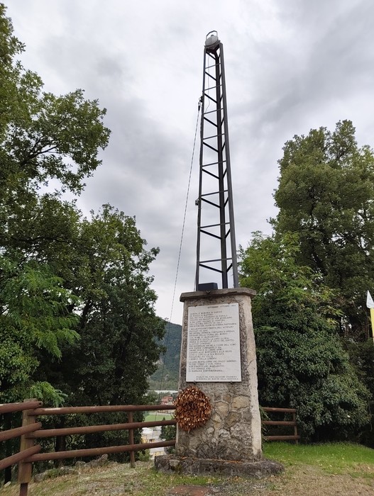 Il Faro è un monumento caratterizzato da una struttura slanciata, circondato da alberi e con un cielo nuvoloso.