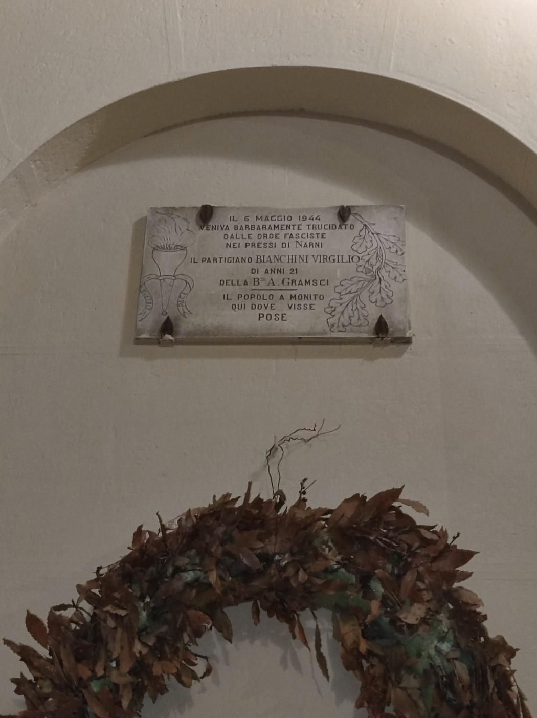 Lapide commemorativa dedicata a Bianchini, con decorazioni floreali e un ramoscello d'alloro.