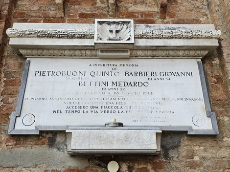 Lapide commemorativa dedicata a Pietrobuoni, Barbieri e Bettini, incisa su pietra, in un contesto storico.