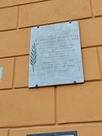 Lapide commemorativa in onore di Fernando Nuccitelli, patriota e combattente, affissa su una parete.