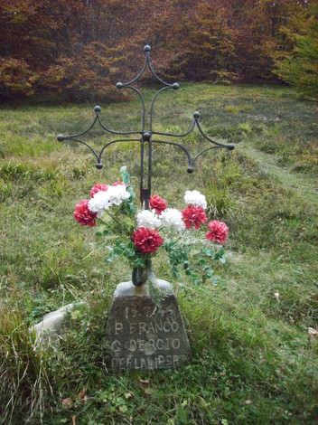 Cippo commemorativo decorato con fiori, immerso nella natura, in memoria di Giovannetti e Prioreschi.