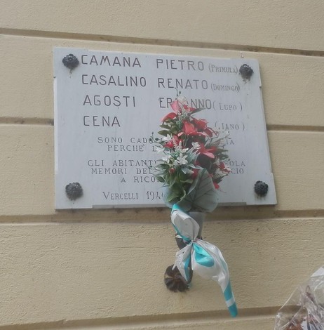 Lapide commemorativa dedicata ai caduti per la libertà, adornata con un mazzo di fiori.