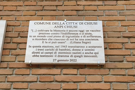 Lapide commemorativa dedicata ai deportati, con riferimenti alla memoria e alla sofferenza umana.