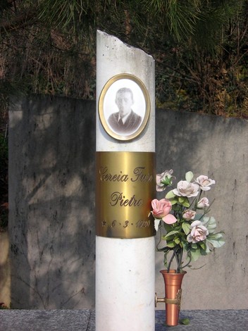 Monumento commemorativo dedicato ai martiri della Garella, con decorazioni floreali e un ritratto.