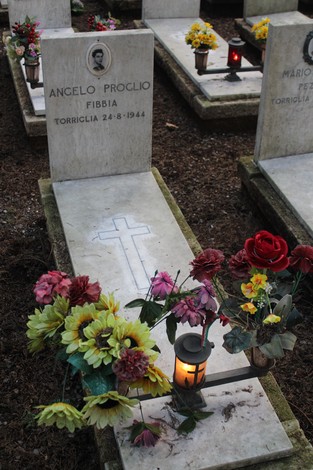 Tombe con fiori e candele in memoria dei caduti per la Libertà, evidenziando il rispetto e il ricordo.