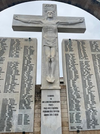Monumento al sacrificio nel "Campo della Gloria", con croce e pannelli commemorativi di caduti in guerra.