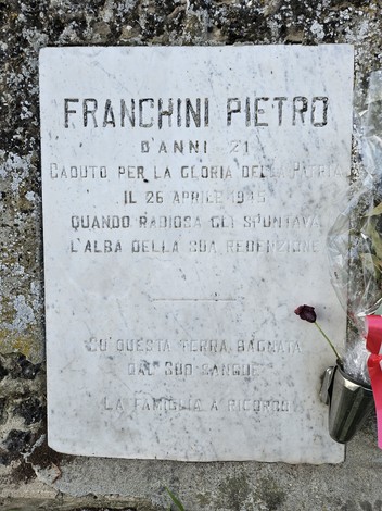Cippo commemorativo dedicato a Franchini Pietro, con una rosa e un messaggio di ricordo.