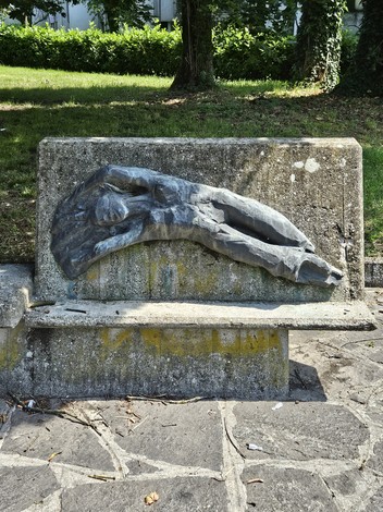Monumento alla Resistenza, scultura in bronzo che rappresenta un corpo disteso su una panchina in un parco.