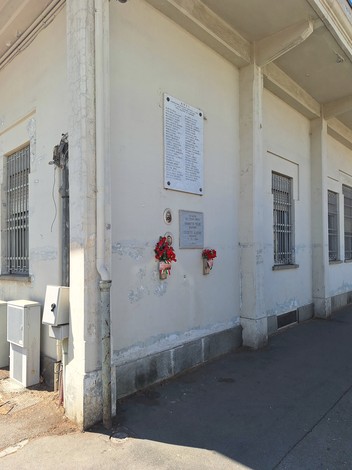 Lapide commemorativa a Chiabotto e Crosetto su una parete esterna, adornata da fiori.