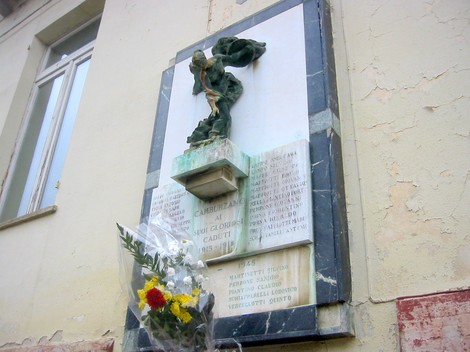 Lapide commemorativa ai caduti di Camburzano, con decorazioni e fiori in omaggio alla memoria.