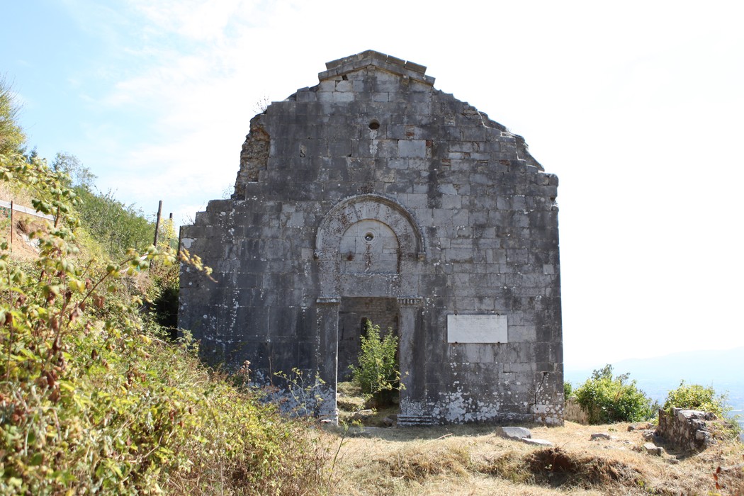 Lapide commemorativa per il quarantennale della Liberazione, su un rudere storico immerso nella natura.