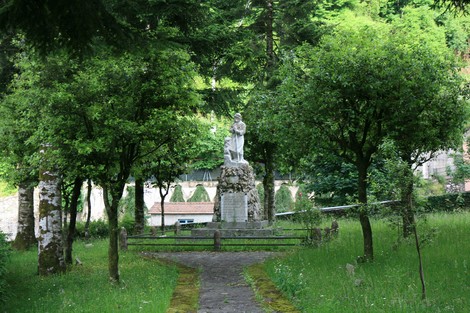 Monumento ai caduti di Mulina, immerso nel verde, circondato da alberi e un sentiero accogliente.