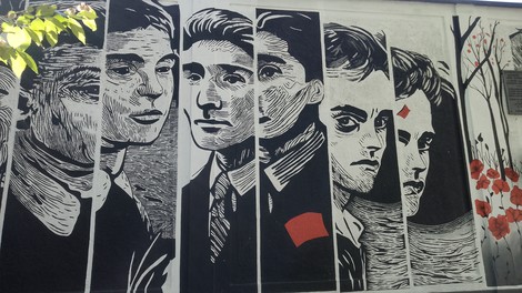 Murale che ritrae volti espressivi dei ragazzi di Via Botticelli, con dettagli in bianco e nero.