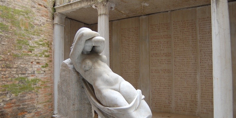 Scultura nel "Sacrario degli studenti universitari caduti", con colonne e iscrizioni commemorative sullo sfondo.