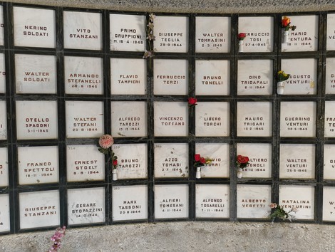 Monumento Ossario dei caduti partigiani, con nomi incisi e fiori in memoria dei combattenti.