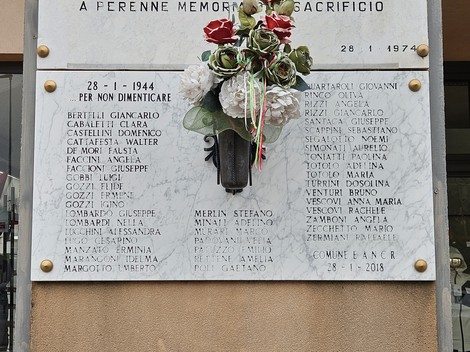 Lapide commemorativa per il bombardamento del 28 gennaio 1944, con nomi delle vittime e decorazioni floreali.