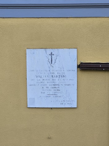 Lapide commemorativa dedicata a Walter Martani, affissa su una parete di color giallo.