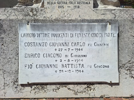 Lapide in marmo con iscrizione dedicata alle vittime, fissata su un basamento in pietra all'aperto.
