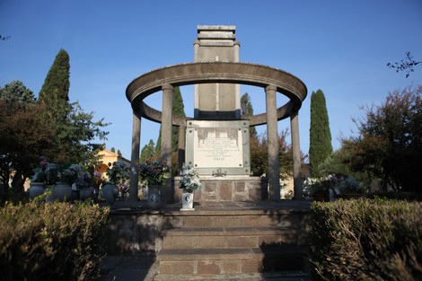 Sacrario ai caduti con monumento, circondato da piante e fiori, in un ambiente sereno e curato.