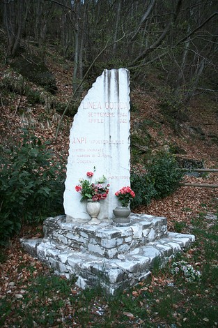 Monumento alla Linea Gotica, commemorazione storica immersa nella natura. Fiori adornano la base in pietra.