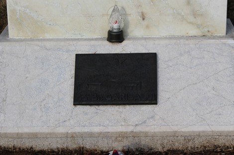 Lapide commemorativa dedicata ai caduti, con un oggetto luminoso nella parte superiore.