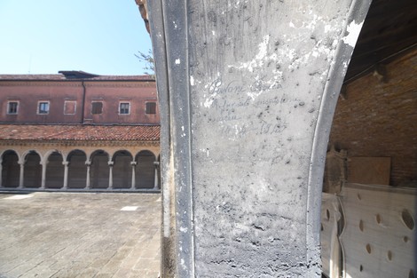 Iscrizione su un muro in un contesto storico, evocando la memoria di rifugiati dai bombardamenti.