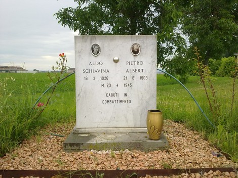 Monumento commemorativo a Aldo Schiavina e Pietro Alberti, caduti in combattimento, circondato da erba e fiori.