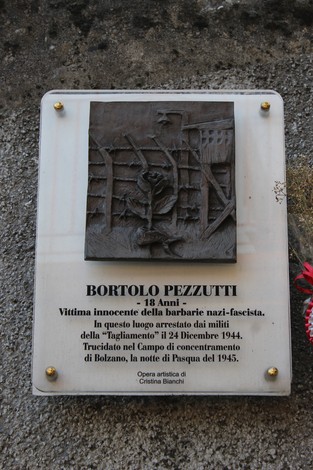 Targa commemorativa dedicata a Bortolo Pezzutti, vittima della violenza nazifascista, con relief artistico.