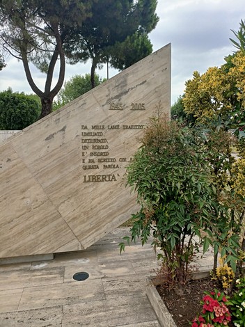 Monumento alla libertà con un design moderno, circondato da vegetazione e alberi, simbolo di emancipazione e speranza.