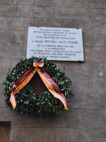 Lapide commemorativa dedicata a Nicola Stame, con una corona di alloro, affissa su un muro.