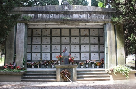 Monumento commemorativo con lastre in onore dei caduti per la Liberazione, adornato di fiori e decorazioni.