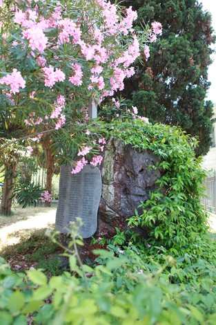 Monumento ai caduti del Lido, con piante e fiori che lo circondano, posto in un ambiente naturale e sereno.