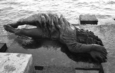 Monumento alla partigiana, scultura di una figura distesa su una banchina, immersa in un ambiente acquatico.
