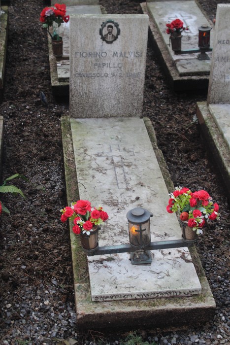 Tombe commemorative con fiori e luci in memoria dei caduti per la Libertà. Atmosfera di rispetto e commemorazione.