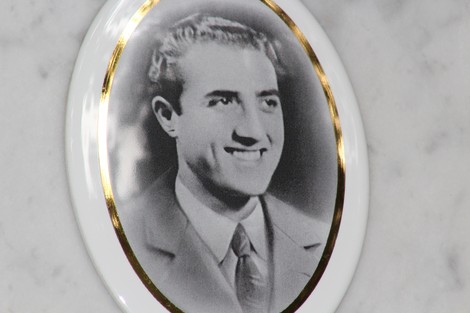 Ritratto in bianco e nero di un giovane uomo sorridente, incorniciato in un ovale ceramico.