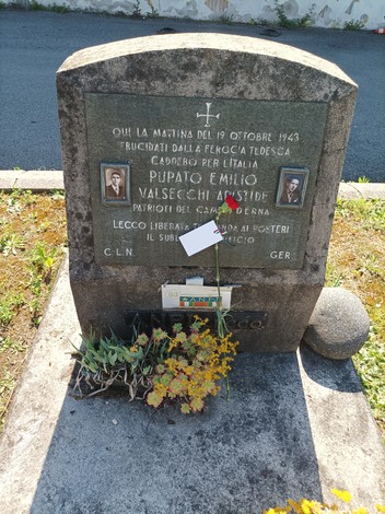 Cippo dedicato a Pupato e Valsecchi, patrioti caduti nel 1943, con fiori e una rosa rossa sul monumento.