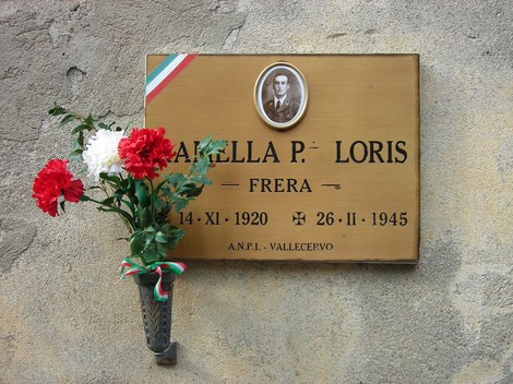 Targa commemorativa dedicata a Loris Ramella, con fiori e simboli tricolori, in memoria del suo sacrificio.