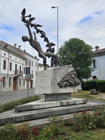 Monumento alla Resistenza con sculture che raffigurano figure umane e uccelli, in un contesto urbano tranquillo.