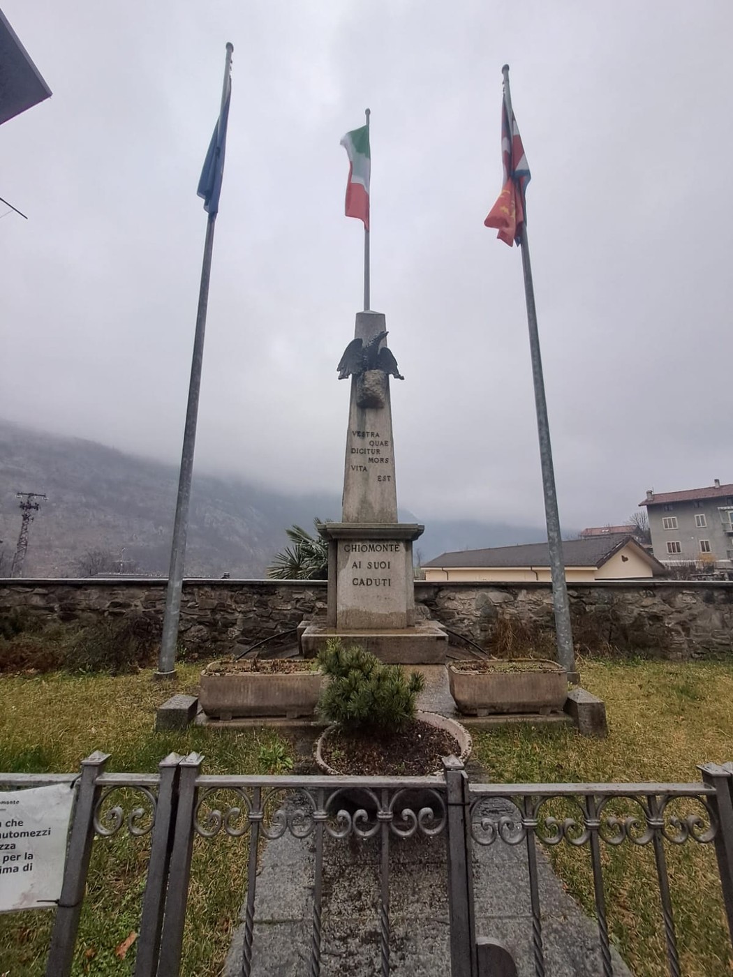 Monumento ai caduti di Chiomonte, eretto in memoria delle vittime locali. Ambiente suggestivo con bandiere.
