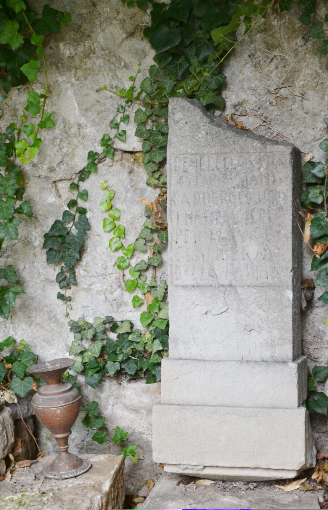 Cippo commemorativo ai partigiani caduti nella battaglia di Benedello, circondato da vegetazione.
