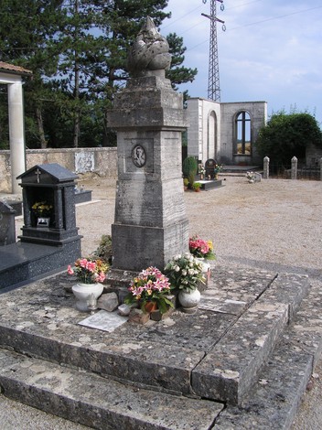 Monumento commemorativo ai partigiani, circondato da fiori e pietre, in un contesto di quiete e memoria.
