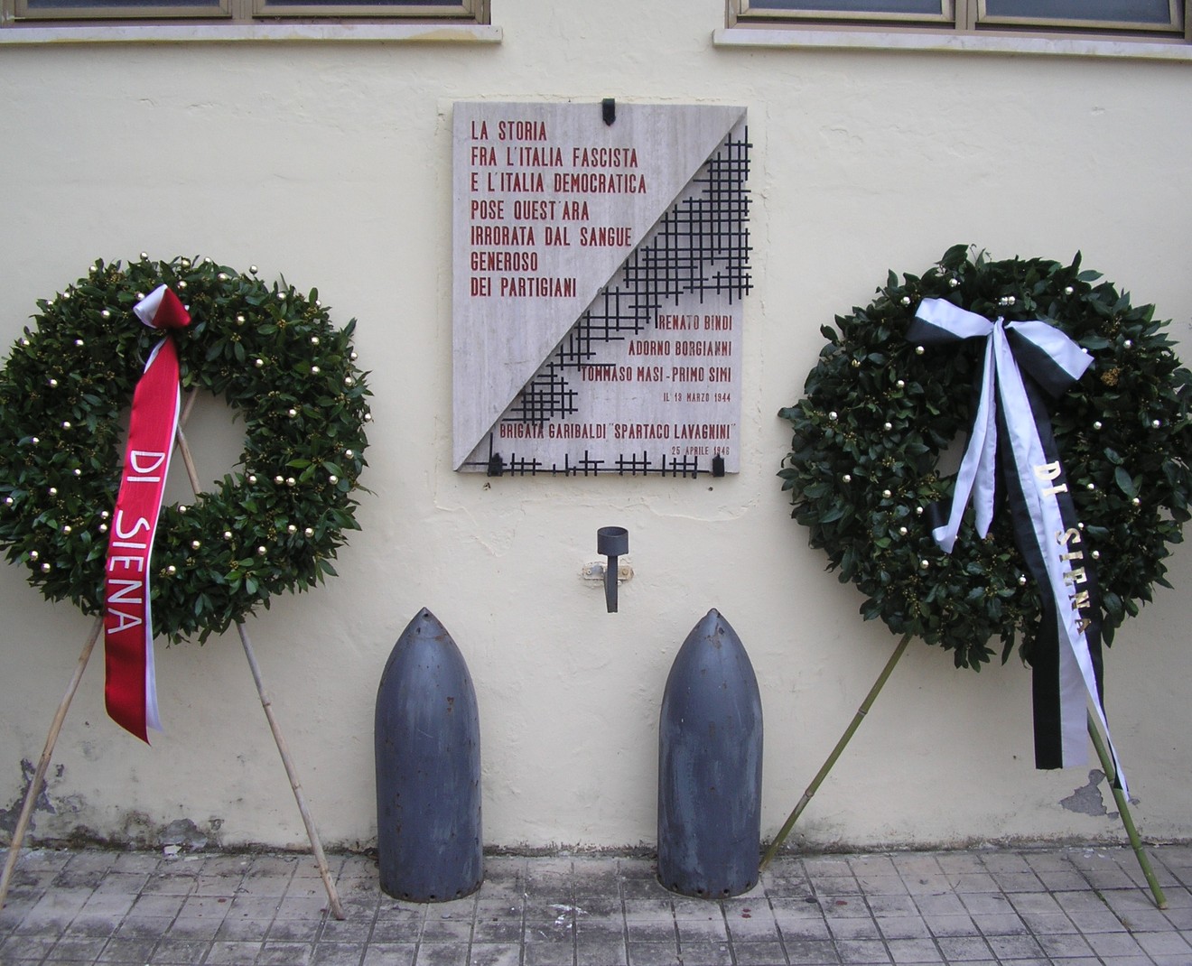 Lapide commemorativa all'ingresso della Caserma Lamarmora, con corone di fiori a memoria dei partigiani.